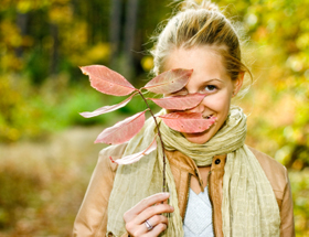 Attraktivität: Frau schaut durch ein Herbstblatt