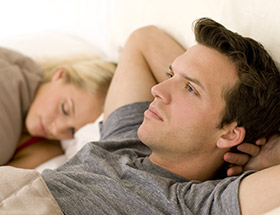 Beziehungsprobleme: Paar liegt unglücklich im Bett