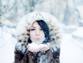 eDarling-Gutschein: Frau mit Mütze pustet Schnee in die Kamera