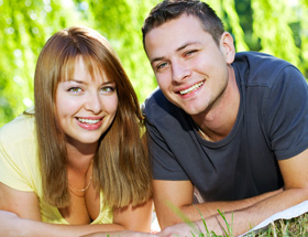 Jüngerer Mann: Mann und Frau liegen auf Bauch und schauen lachend in Kamera