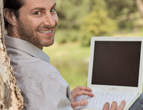 Romance Scamming: Mann surft über Laptop im Internet
