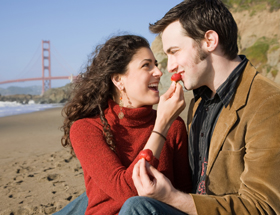 Sachen, die man aus liebe tut: Frau füttert Freund am Strand mit Erdbeere